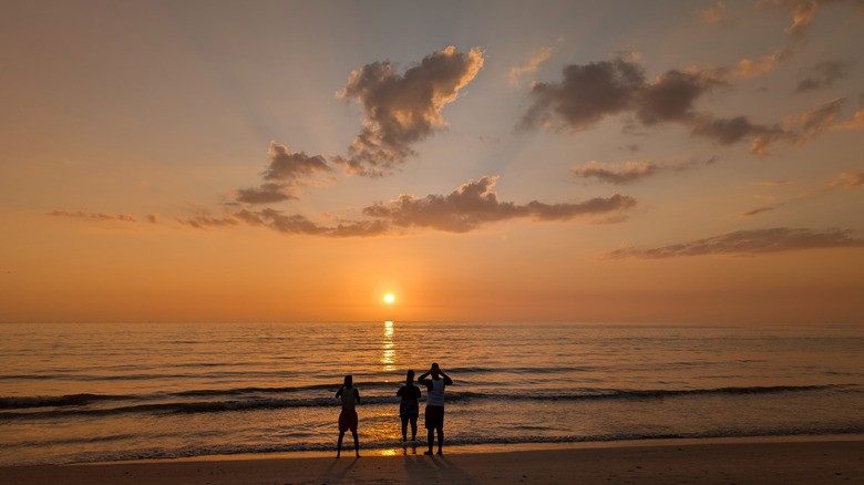 family watching sunset on the shores of pass a grille beach, florida