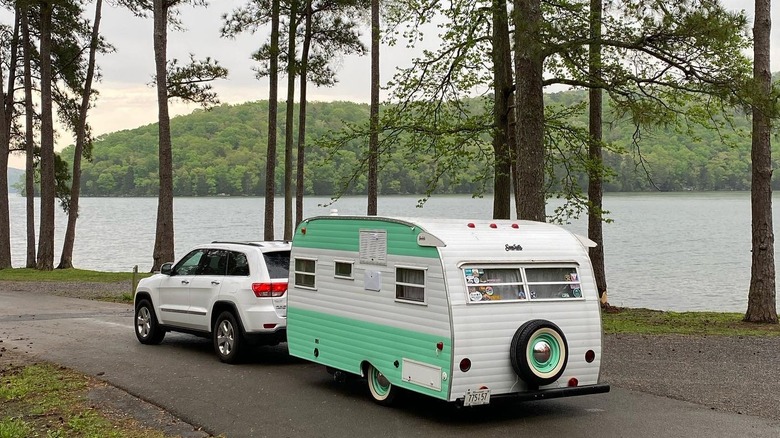 An SUV towing a vintage camper by a Guntersville Lake