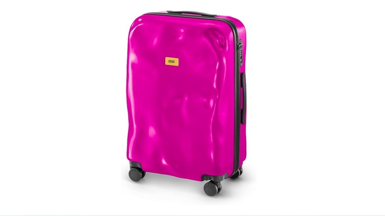 Close-up of Crash Baggage's medium-size Icon suitcase in fuschia with dents in its exterior