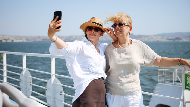 Younger woman takes selfie with older woman next to her on ship deck