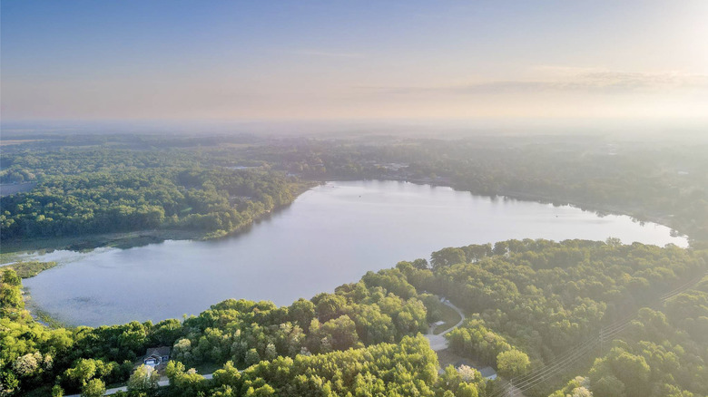 An aerial view of Stone Lake surrounded by trees as the sun sets in Cass County, Michigan