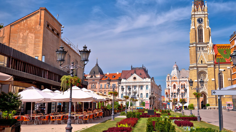A picturesque street in Novi Sad, Serbia with outdoor cafes and a cathedral in the distance