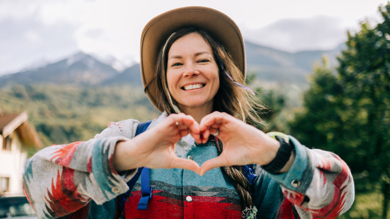 A smiling woman making a heart by joining her hands together