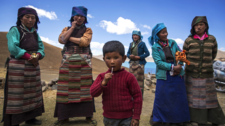 A group of women and a child stand in front of a lake in Tibet