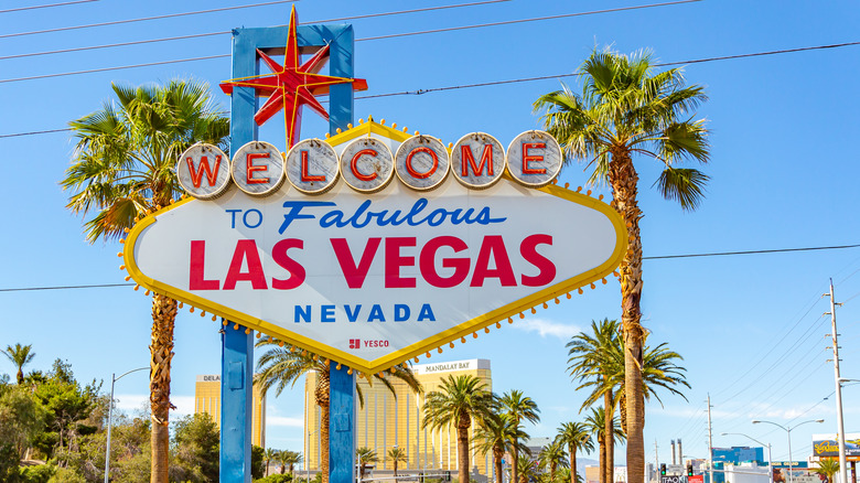 Daytime image of the "Welcome to Fabulous Las Vegas Nevada" sign at the start of the Strip (Las Vegas Boulevard), with blue skies and lush palm trees visible in the background