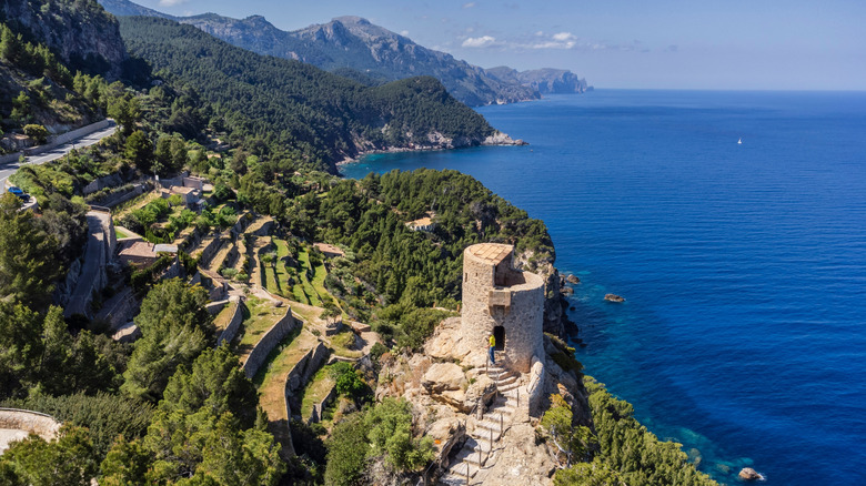 Stone tower on terraced fields overlooking the coastline, with Serra  de Tramuntana mountains in the distance, Mallorca