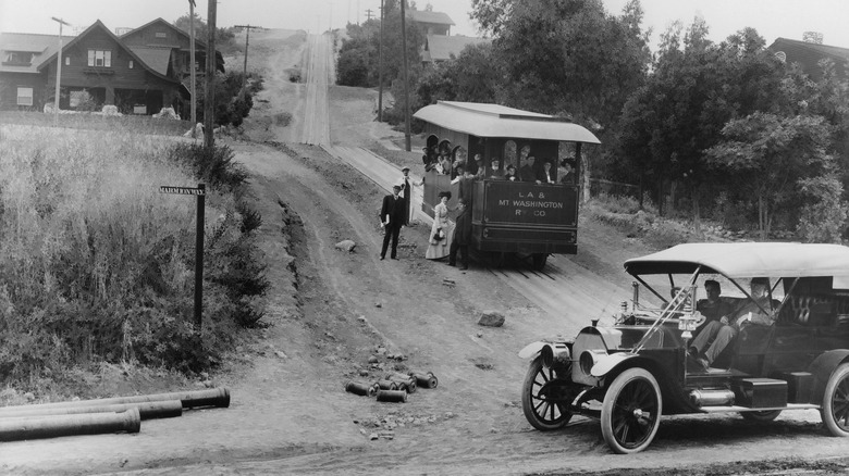 Mount Washington streetcar in Highland Park, California, in the early 1900s carrying passengers up a hill as motor car passes on adjacent road