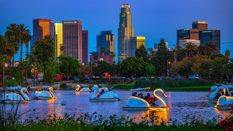 View of Downtown Los Angeles skyline at sunset from Echo Park, featuring swan pedal boats on the lake