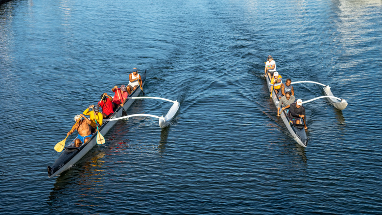 Hwaiian men racing in an outriggered canoe in Honolulu