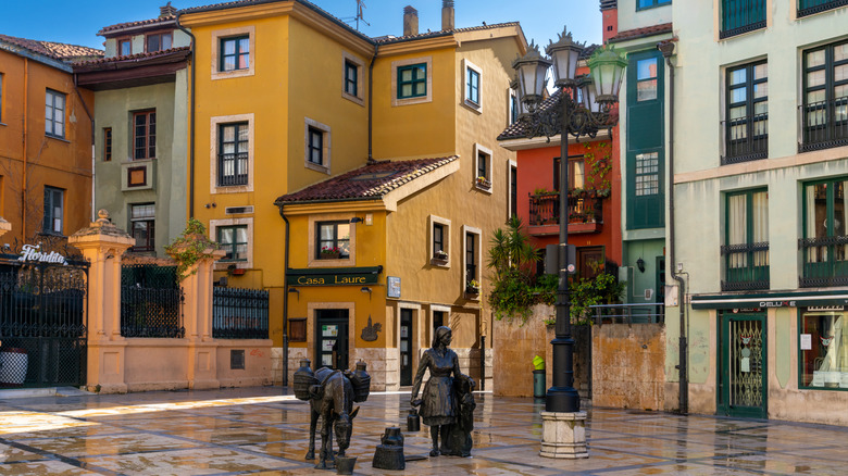 Donkey and milkmaid statues in the center of Old Town Oviedo, backed by colorful buildings