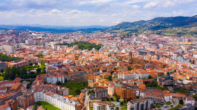 Aerial view of red roofs and buildings backed by mountains in Oviedo, Spain