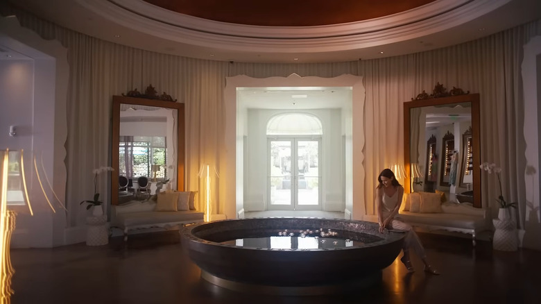 Woman in dress sits by oversized tub at The Eau spa.
