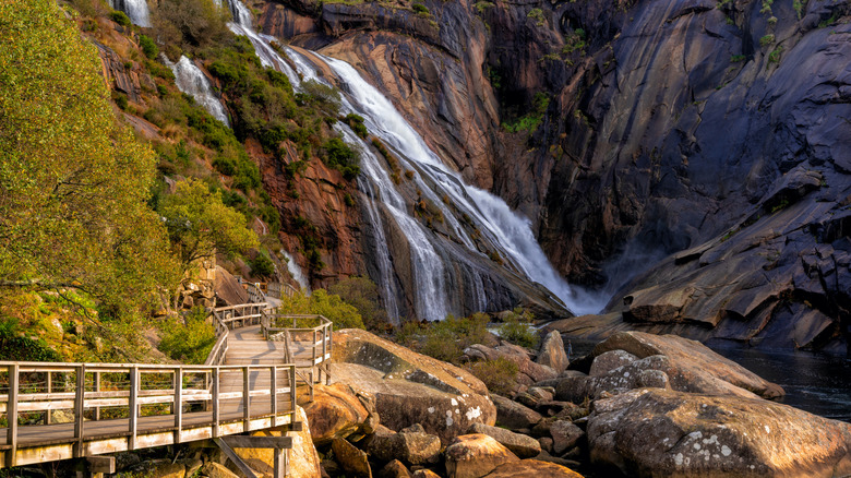 A waterfall in front of a wooden boardwalk in a canyon