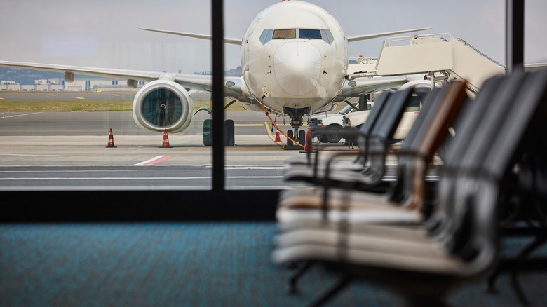 A large jet gets refueled, as seen through an airport window