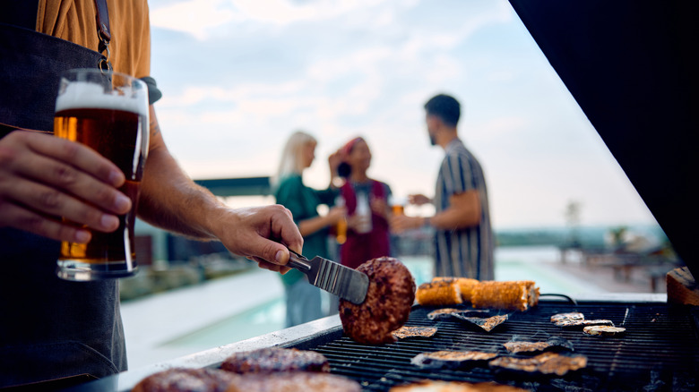 Man grilling some meats with beer in hand