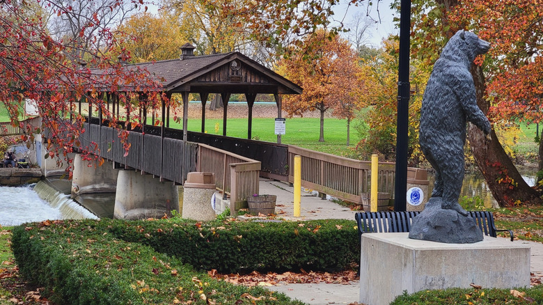 Wooden covered bridge over the Flat Rock Dam, with a bear statue nearby