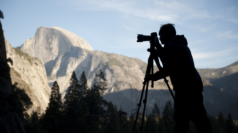 Shadow of a man with a camera tripod in front of a blurry view of Yosemite National Park