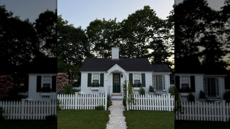 A small white cottage with green shutters and a white picket fence at The Dunes on the Waterfront in Ogunquit, Maine