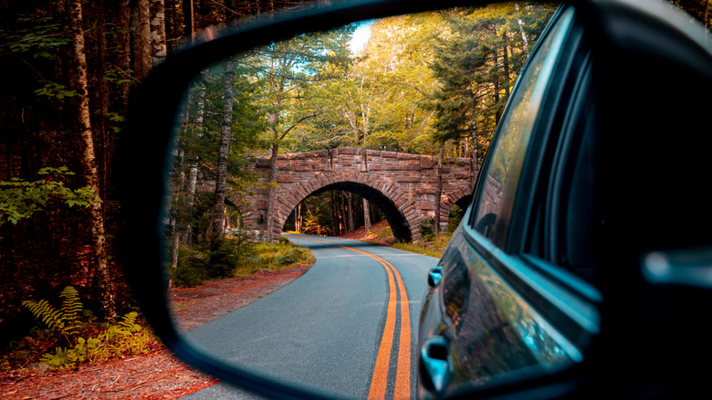 View of Acadia National Park's historic bridge on a car's rearview mirror.