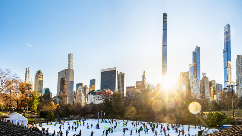 Ice skating in Central Park with skyline of New York in the background