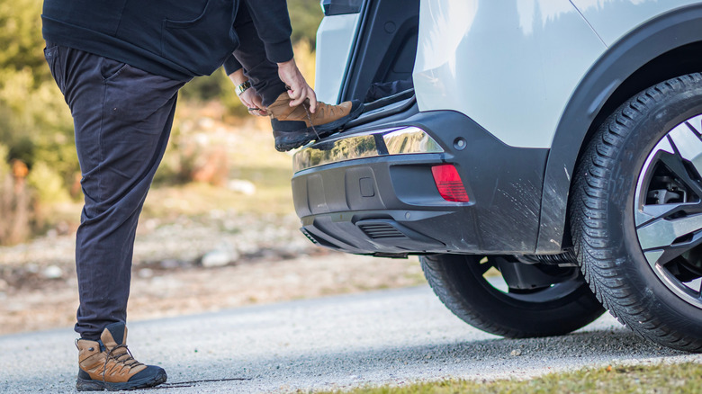 A hiker ties his shoes on his car at a Texas state park.