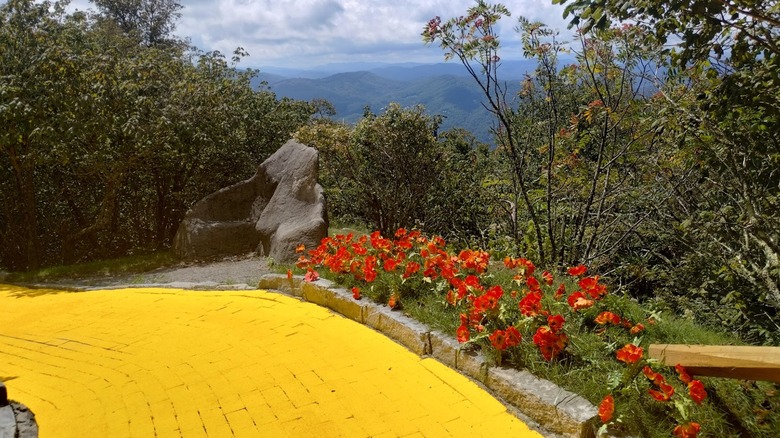 Yellow brick road surrounded by trees and wildflowers with mountains in background Land of Oz North Carolina
