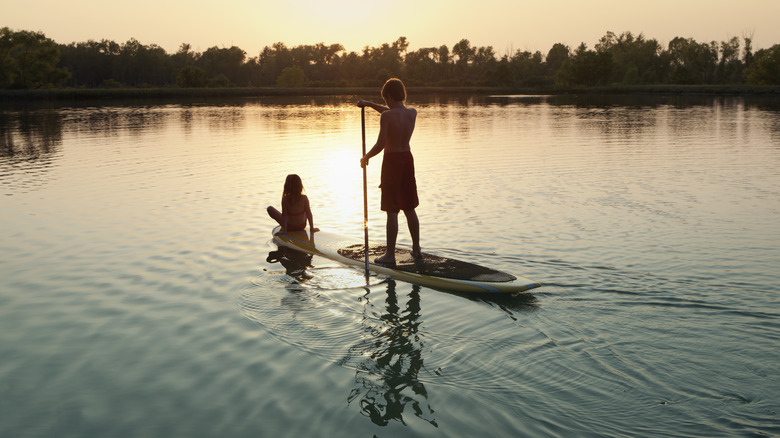 Boy and girl paddleboarding at sunset