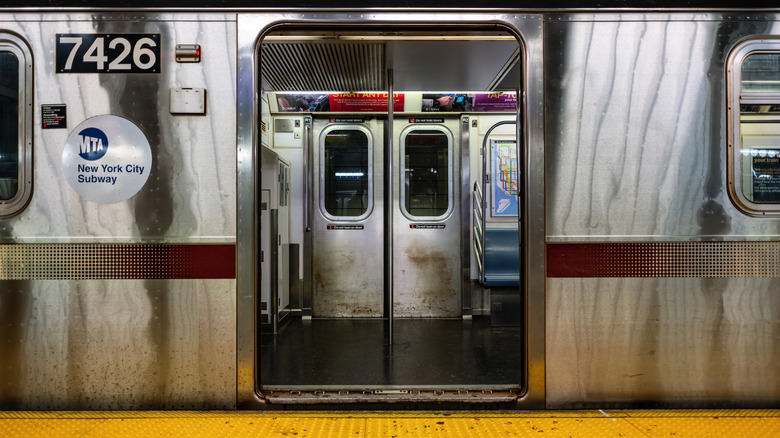 Dirty New York subway train car with open doors, stopped at a platform