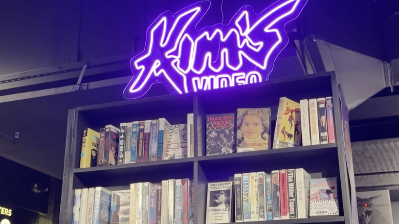 A neon sign that says Kim's Video above a shelf of VHS tapes inside Kim's Video Underground in NYC