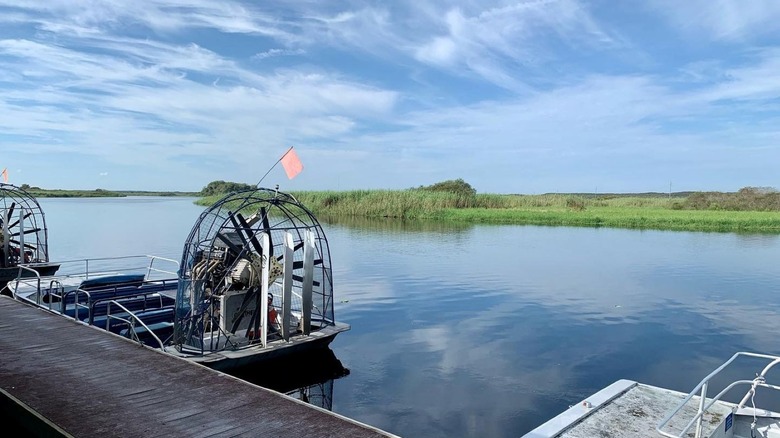 Airboat sitting in water by dock at the Lone Cabbage Fish Camp