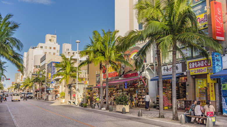 The palm-tree-lined street and colorful storefronts of Kokusai-dori in Naha, Japan
