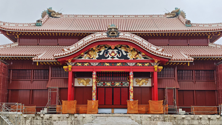 Red-and-gold facade and tiled roofs of Shuri Castle in Naha