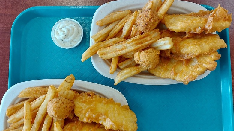 Two orders Fish & Chips on white plates with a side of tartar sauce on a blue tray from Arthur Treacher's Fish & Chips