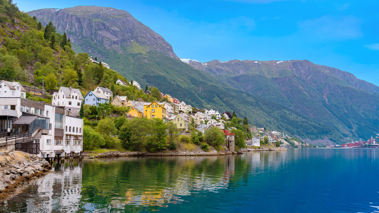 Colorful Norwegian homes perched alongside a fjord in Odda, Hardanger, Norway with mountains