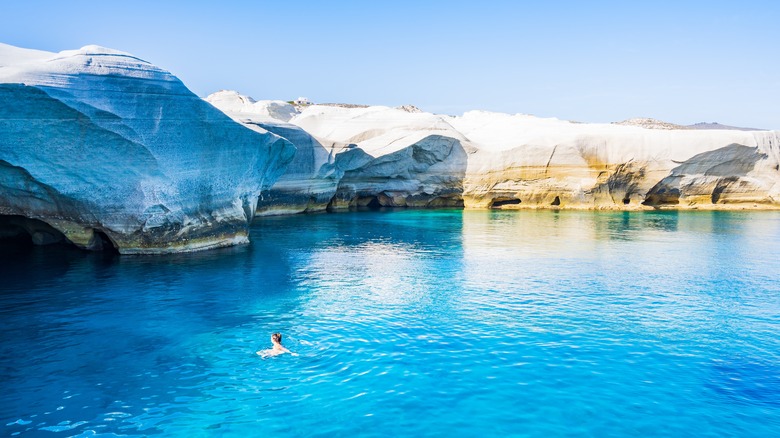 Blue water, white rocks, woman swimming