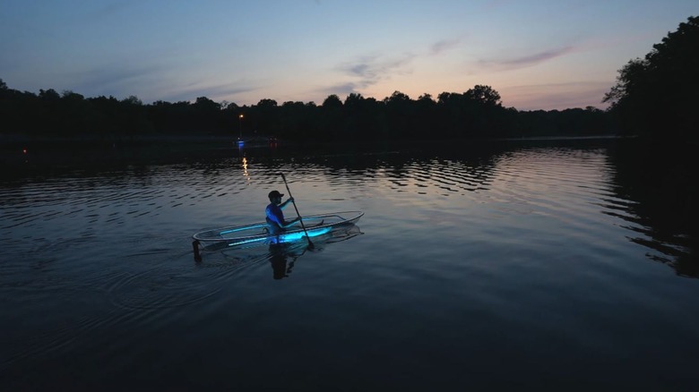 A clear kayak lit with blue LED lights glides along the dark waters in Tennessee.