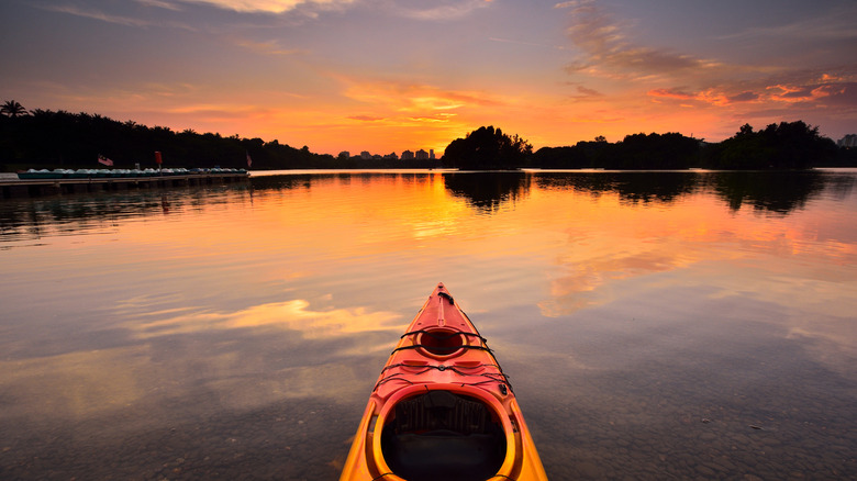 The tip of a kayak on a lake at sunset.