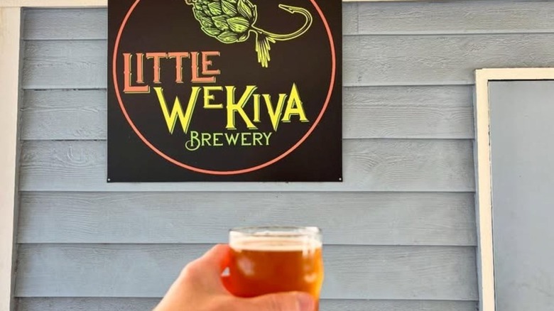 Beer in person's hand with Little Wekiva Brewery sign behind it