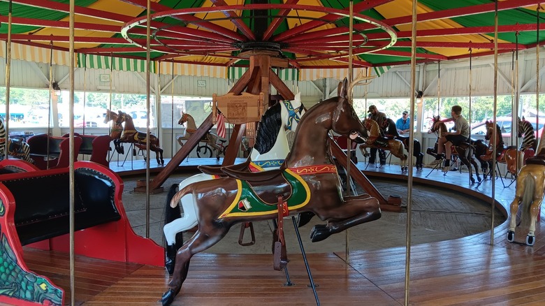 Interior view of the Albion Carousel's animals and chariots with people riding and watching the carousel.