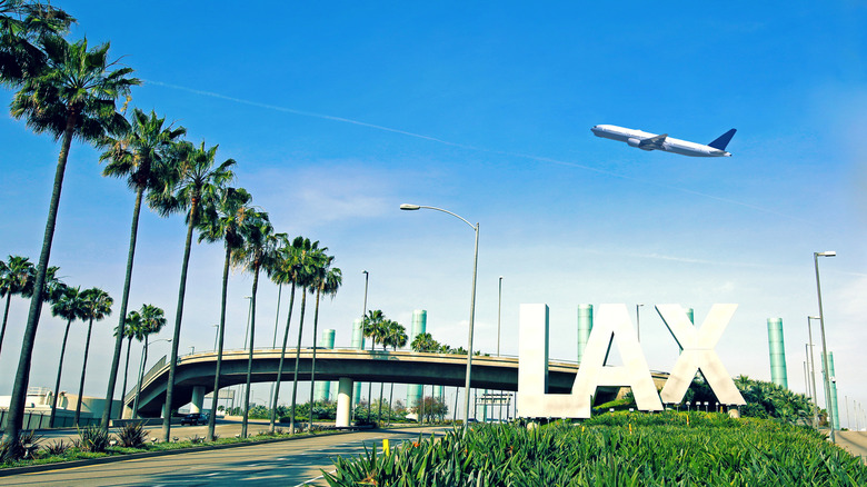 A plane takes off above the LAX sign