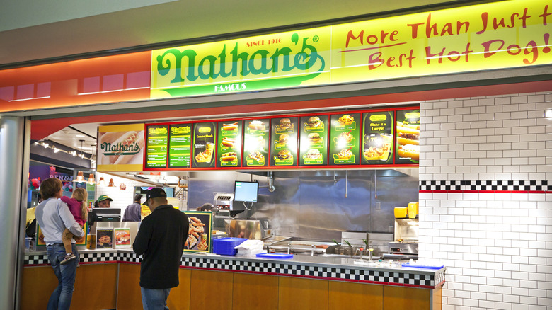 People wait in line at a Nathan's Hot Dogs in Newark International Airport