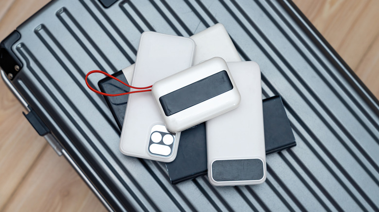 Phones, portable chargers, and other electronic devices on top of a suitcase