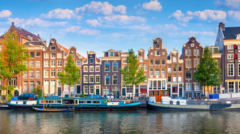 tall buildings and boats line Amsterdam's waterway on sunny day