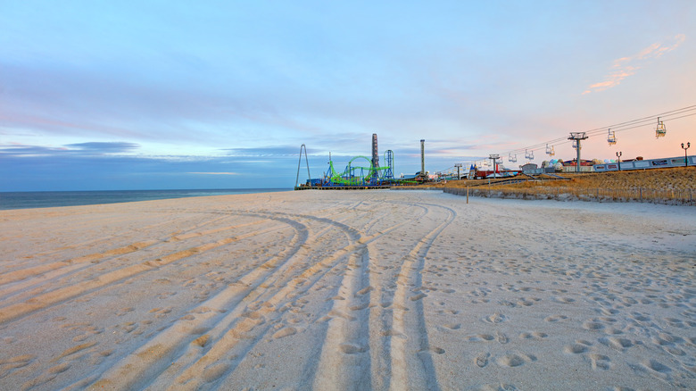 Broad sandy beach with amusement park rides in background at Seaside Heights