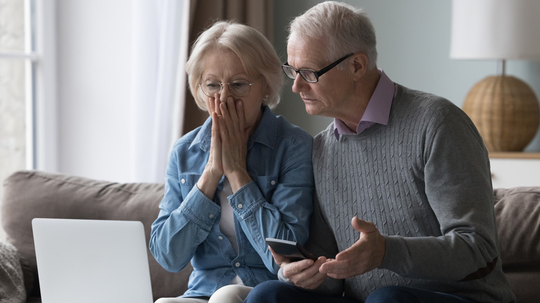 Old couple looking shocked at online bill