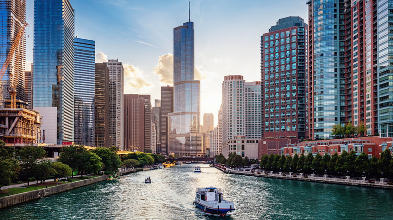 tourists on boats cruise down Chicago River, with the city's famous skyline as a backdrop