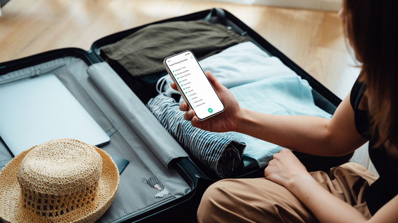 Person using iPhone while packing for a trip