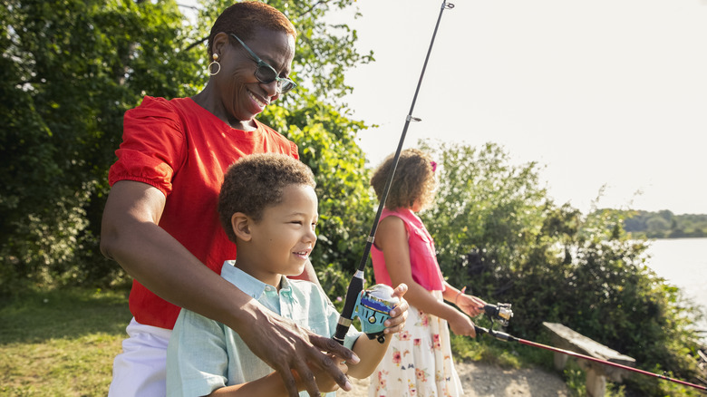 Woman fishing with children on river bank