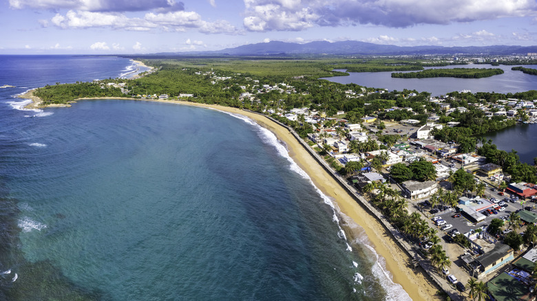 The sandy coastline in Loíza, Puerto Rico, with lush green foliage and coastal buildings