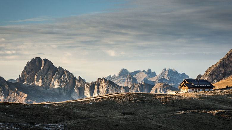 An alpine mountainscape near Aman Rosa Alpina shows a wooden chalet high among the Alps